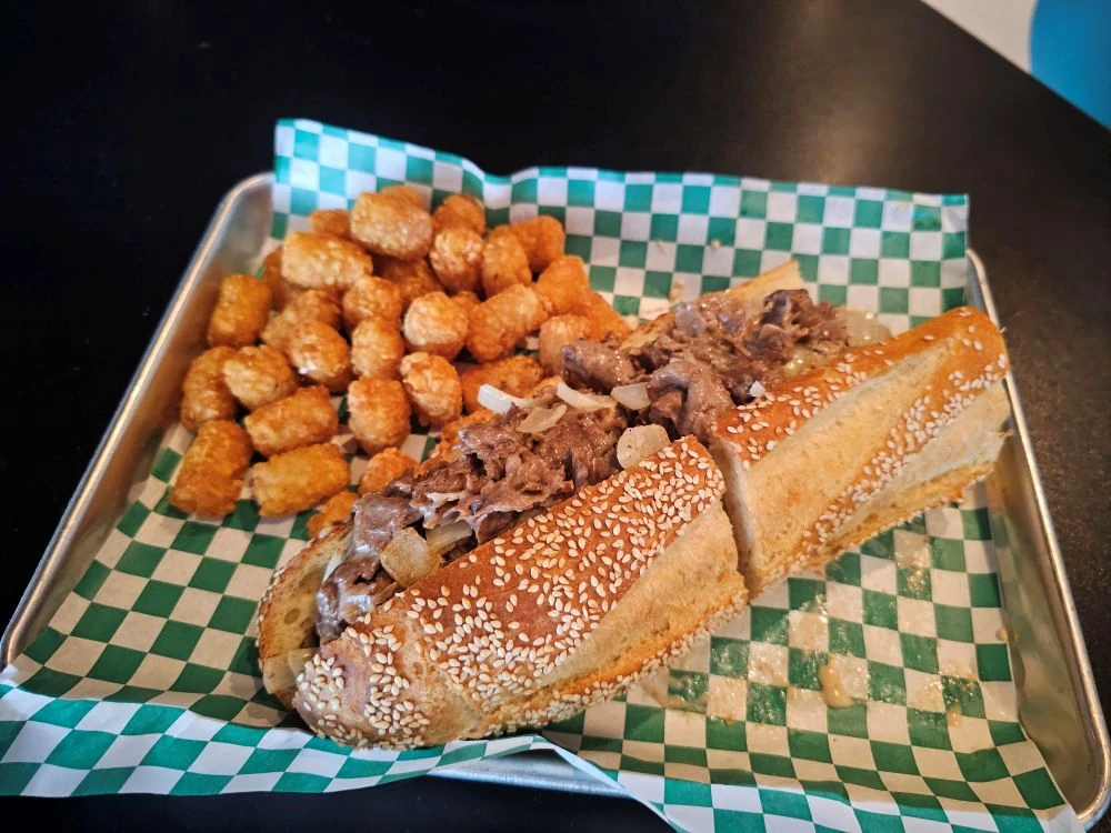 Madison’s Angus ribeye cheesesteak on a seeded roll with tots